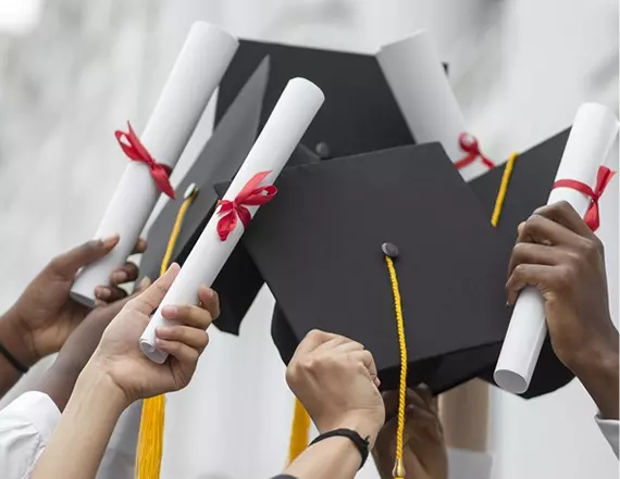 Graduates holding diplomas tied with red ribbon and mortarboards