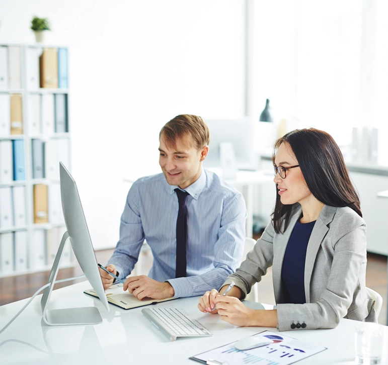 Two colleagues reviewing work together at a computer in an office