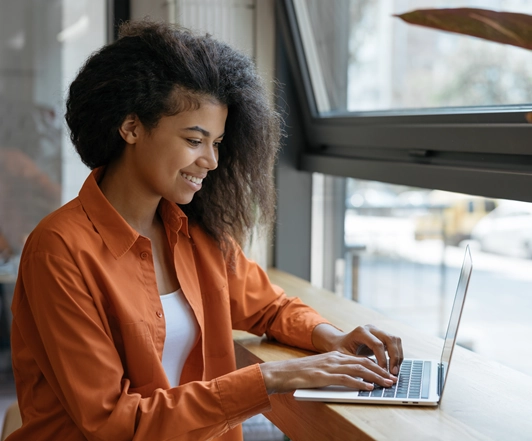 A student working on a laptop by a bright window