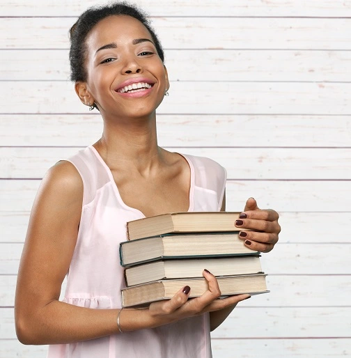 African American woman holding pile of books
