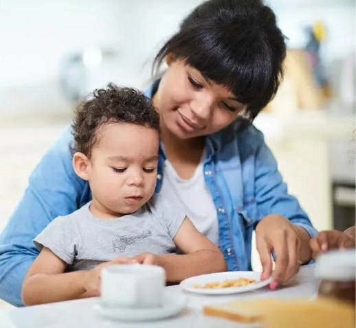 A woman sharing a snack with a young child at a table