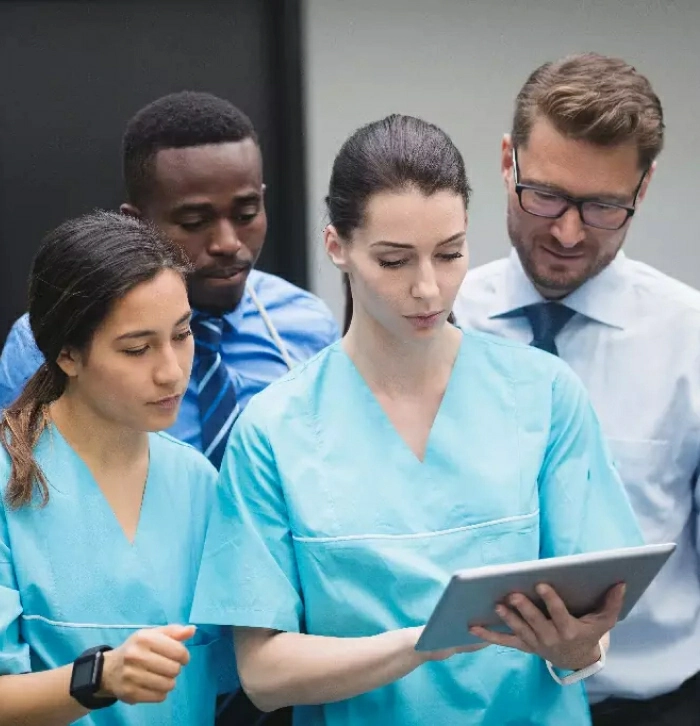 A medical team discussing information on a digital tablet