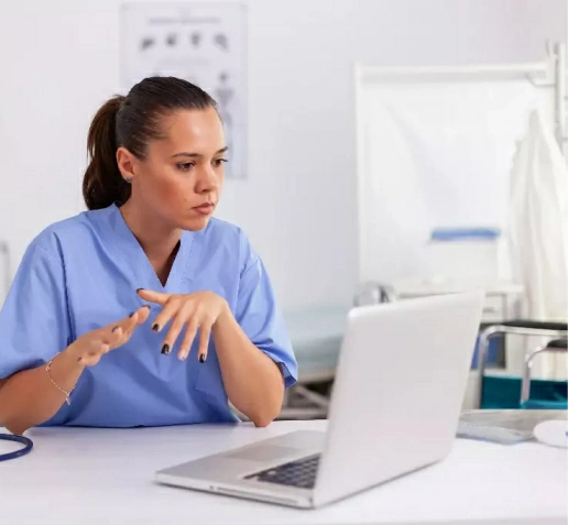 A health care worker reviewing patient information on a laptop at a clinic desk